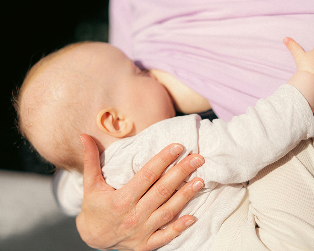 Baby das an der Brust gestillt wird als Symbol für das Elternwerden